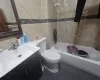 Full bathroom featuring tile patterned floors, toilet,  shower combination, tile walls, and vanity