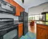 Kitchen with an inviting chandelier, cooling unit, black appliances, and light wood-type flooring