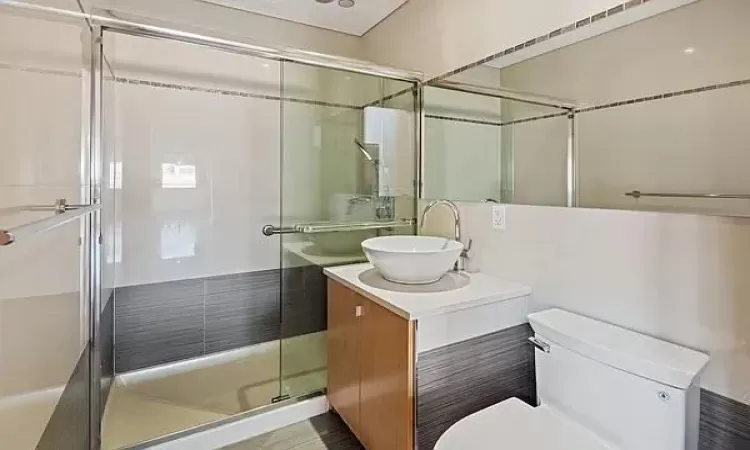 Bathroom with vanity, an enclosed shower, and toilet