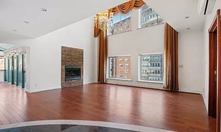 Unfurnished living room with a fireplace, hardwood / wood-style floors, and a notable chandelier