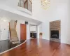 Unfurnished living room with a fireplace, a towering ceiling, wood-type flooring, and a chandelier