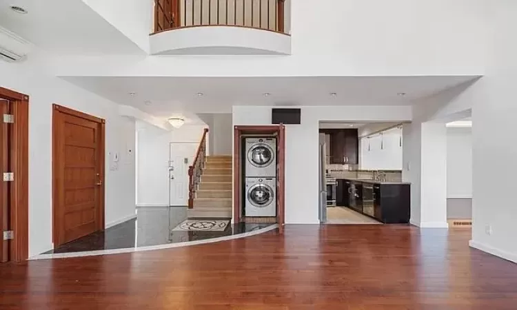 Foyer featuring stacked washer / drying machine, sink, a wall mounted air conditioner, hardwood / wood-style flooring, and a high ceiling