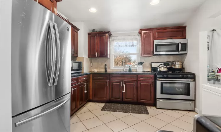 Kitchen featuring stainless steel appliances, tasteful backsplash, sink, and light tile patterned flooring