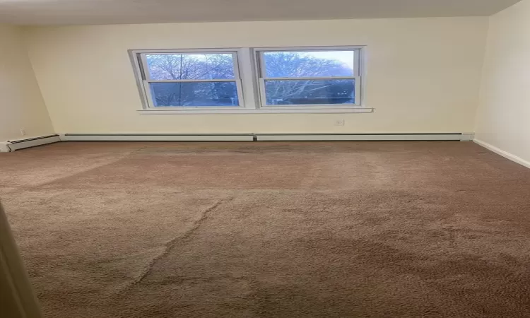 Spare room featuring a healthy amount of sunlight, carpet floors, and baseboard heating