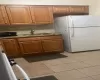 Kitchen featuring backsplash, sink, white fridge, and light tile patterned floors