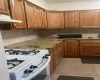 Kitchen with sink, light stone countertops, white gas range, light tile patterned floors, and tasteful backsplash