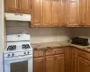 Kitchen with backsplash, light stone counters, and white gas range