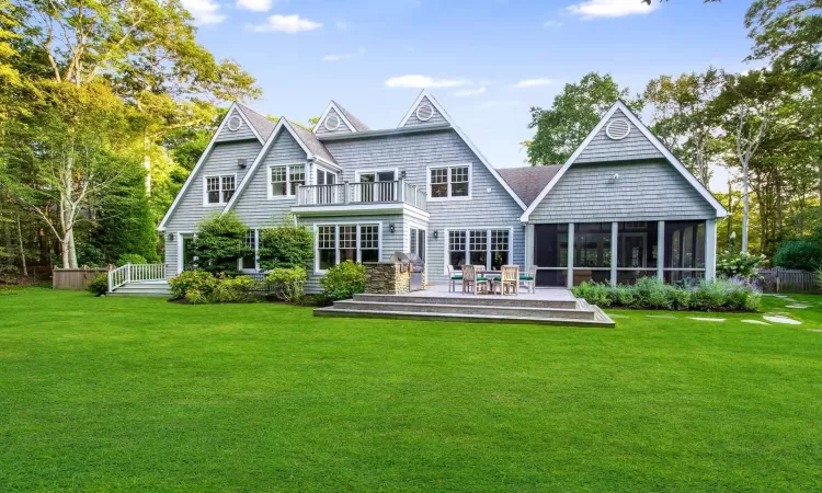 Rear view of property featuring a balcony, a yard, a deck, and a sunroom