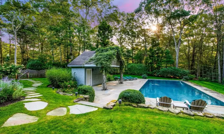 Pool at dusk with an outbuilding, a lawn, and a patio