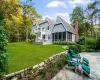 Rear view of house featuring a patio, a sunroom, and a lawn