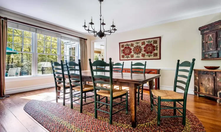 Dining area with hardwood / wood-style flooring, ornamental molding, and an inviting chandelier