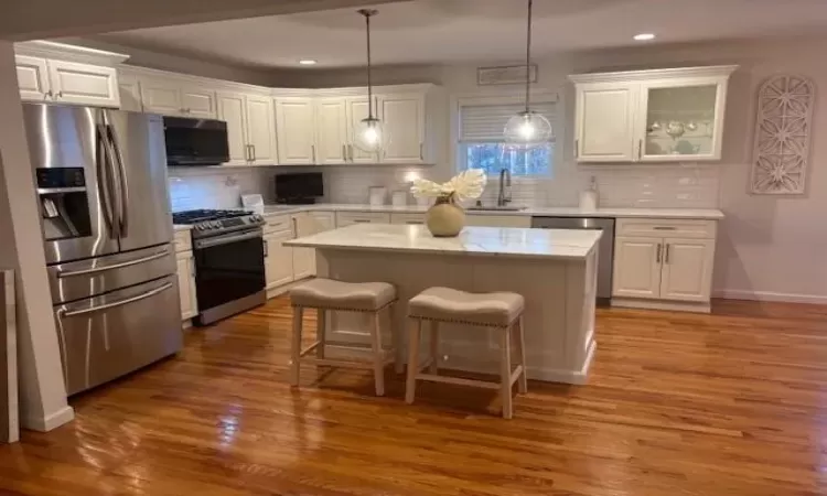 Kitchen with white cabinetry, stainless steel appliances, and a center island