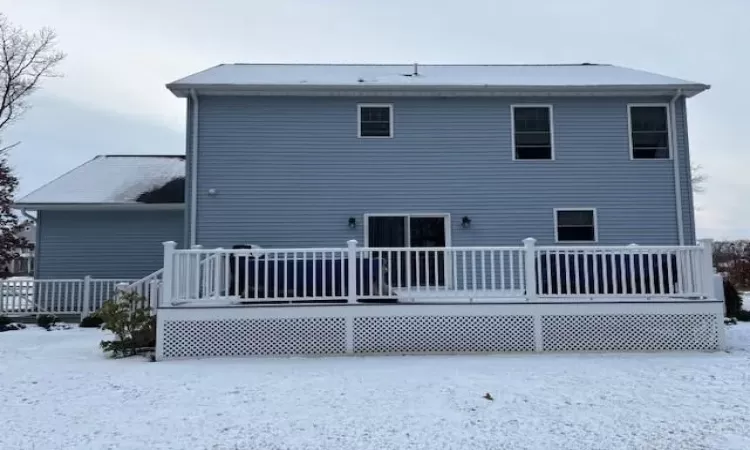 Snow covered back of property with a deck