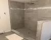 Bathroom featuring a tile shower and baseboard heating