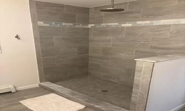 Bathroom featuring a tile shower and baseboard heating