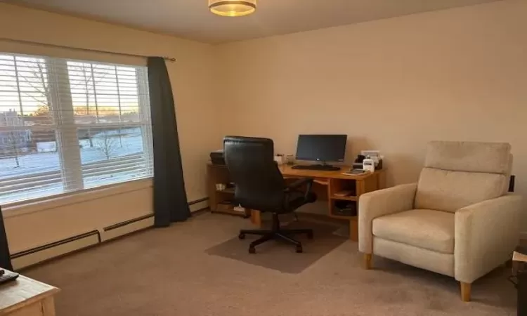 Home office featuring carpet flooring and a baseboard heating unit