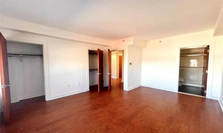 Unfurnished bedroom with dark wood-type flooring and ensuite bath