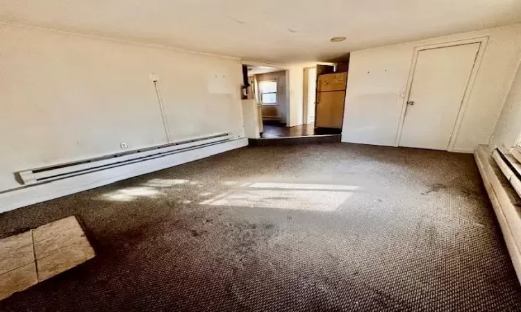 Empty room with a baseboard heating unit and carpet flooring