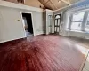 Unfurnished living room featuring wood-type flooring, high vaulted ceiling, a fireplace, and beam ceiling