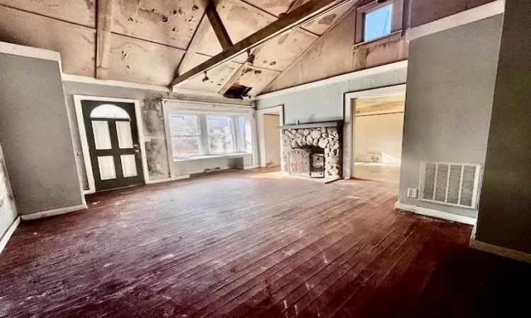 Unfurnished living room featuring wood-type flooring, high vaulted ceiling, a fireplace, and beam ceiling