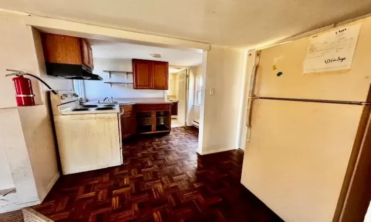 Kitchen with washer / clothes dryer, white appliances, and dark flooring