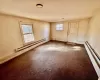 Empty room with a baseboard heating unit and carpet flooring