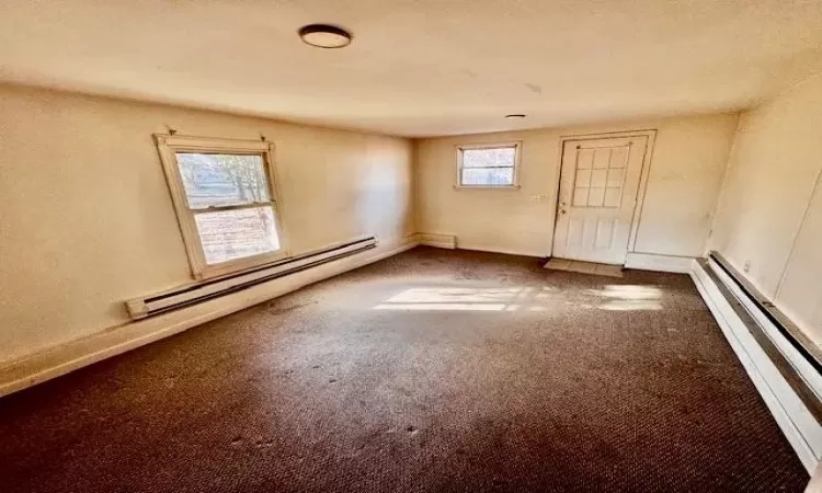 Empty room with a baseboard heating unit and carpet flooring