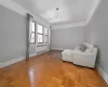 Sitting room featuring light parquet flooring, radiator heating unit, and crown molding