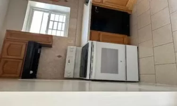 Kitchen featuring dishwashing machine, light tile patterned floors, backsplash, electric range, and ventilation hood