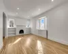 Unfurnished living room featuring built in shelves, a fireplace, and light wood-type flooring