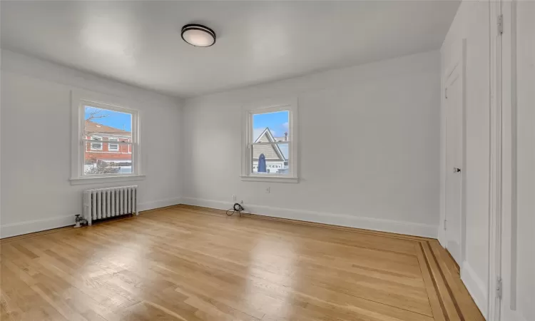 Unfurnished bedroom with radiator and light hardwood / wood-style flooring