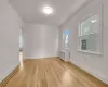 Empty room with crown molding, radiator, and light hardwood / wood-style flooring