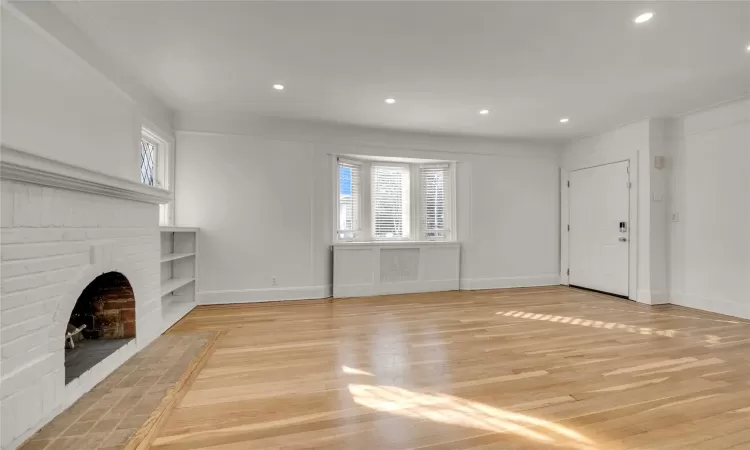 Unfurnished living room with a brick fireplace and light hardwood / wood-style flooring