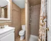 Bathroom with tile walls, tile patterned flooring, vanity, toilet, and a shower with curtain