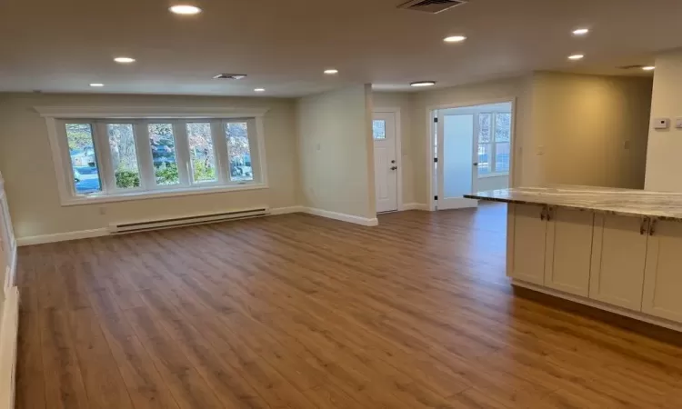 Unfurnished living room featuring a baseboard radiator and dark wood-type flooring