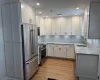 Kitchen featuring white cabinetry, wood-type flooring, sink, light stone counters, and stainless steel appliances