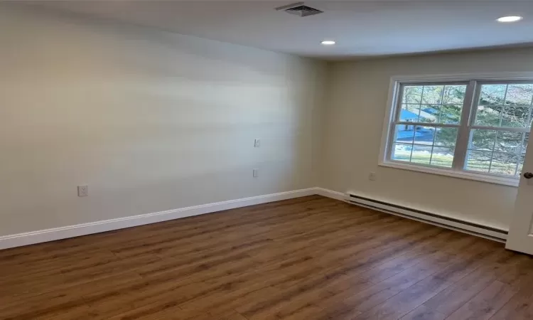 Spare room with a baseboard heating unit and dark hardwood / wood-style floors