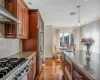 Kitchen featuring sink, dark stone counters, hanging light fixtures, appliances with stainless steel finishes, and wall chimney exhaust hood