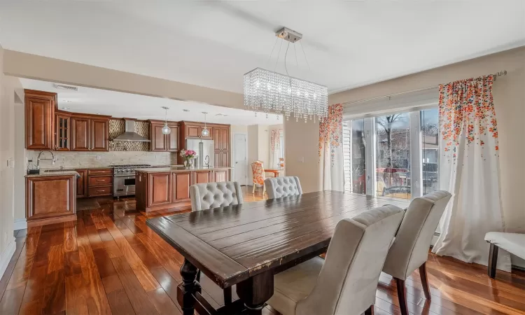 Dining room featuring dark wood-type flooring, sink, and a chandelier