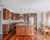 Kitchen featuring a center island, decorative light fixtures, wall chimney range hood, stainless steel appliances, and sink