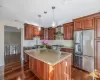 Kitchen featuring wall chimney exhaust hood, decorative light fixtures, stainless steel appliances, sink, and light stone counters