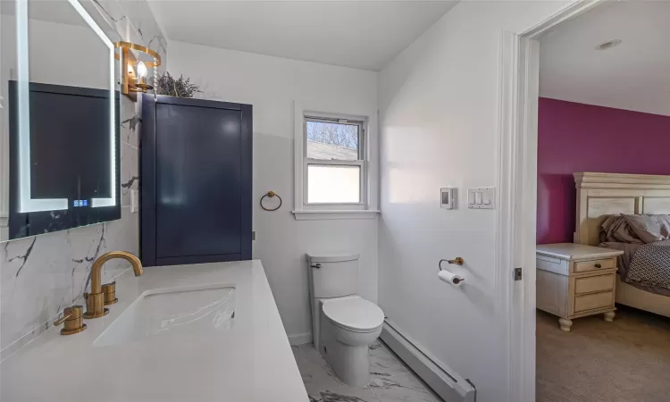 Bathroom with a baseboard heating unit, toilet, and sink