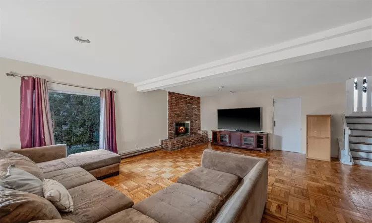 Living room with a brick fireplace, light parquet floors, and beamed ceiling