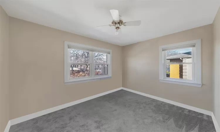 Spare room with dark colored carpet and ceiling fan