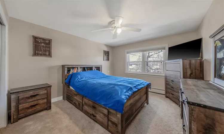 Bedroom featuring a baseboard heating unit, ceiling fan, and light carpet