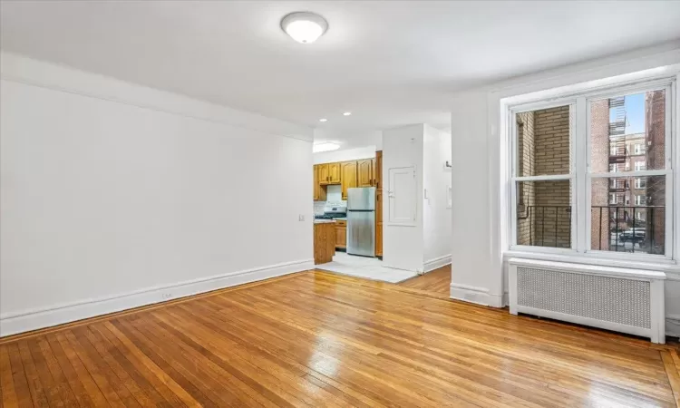 Unfurnished living room featuring radiator heating unit and light hardwood / wood-style floors