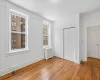 Unfurnished bedroom featuring radiator, hardwood  floors, and a large closet