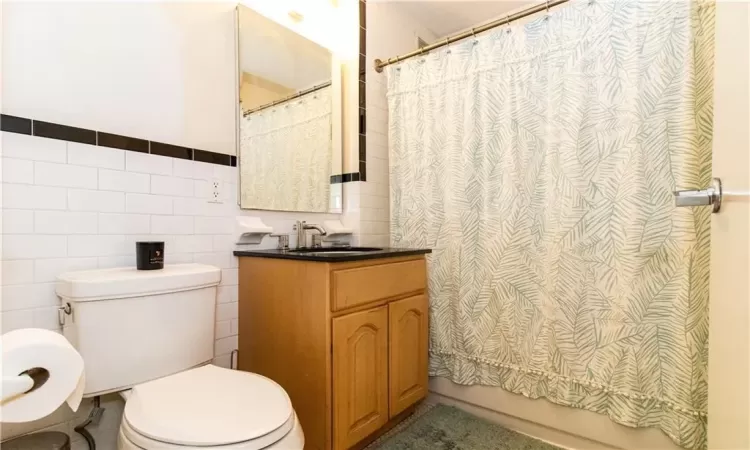 Bathroom with vanity, toilet, and tile walls