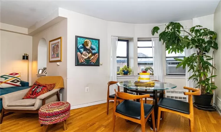 Dining room with radiator heating unit, hardwood / wood-style floors, and cooling unit