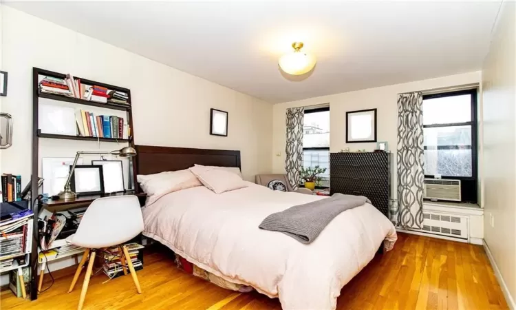 Bedroom featuring cooling unit, radiator heating unit, and wood-type flooring